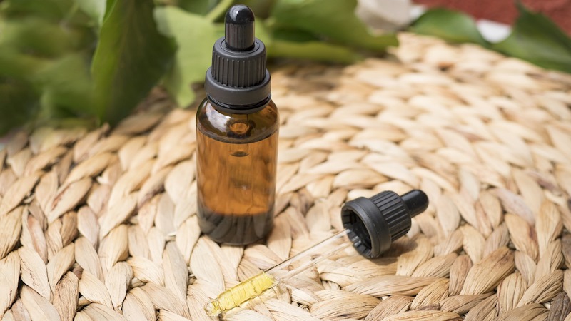 A squeeze dropper on a wicker plate with medication in the vial.