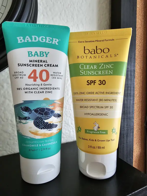 Badger brand and babo brand sunscreen cream bottles on a shelf.