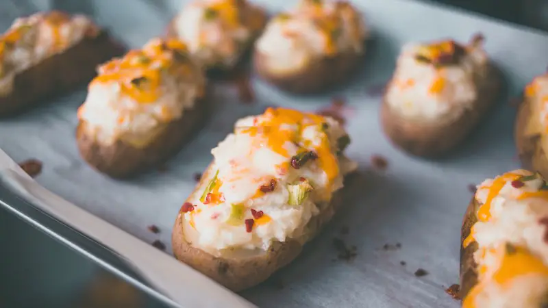A tray full of loaded baked potatoes hot out of the oven. Fact: Potatoes are not high in histamine.