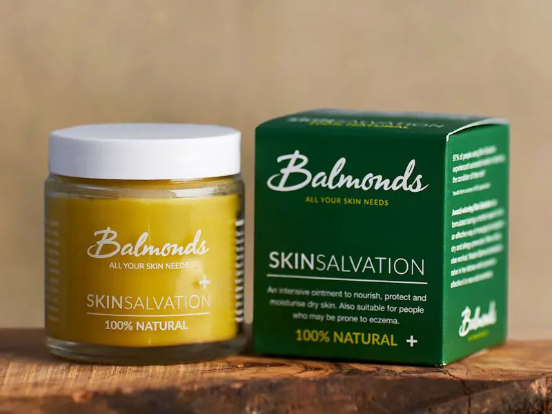 A jar of Balmonds SkinSalvation ointment next to a box of the same moisturizer. The box states this cream is to protect and moisturize for dry skin, and also suitable for people who may be prone to eczema.