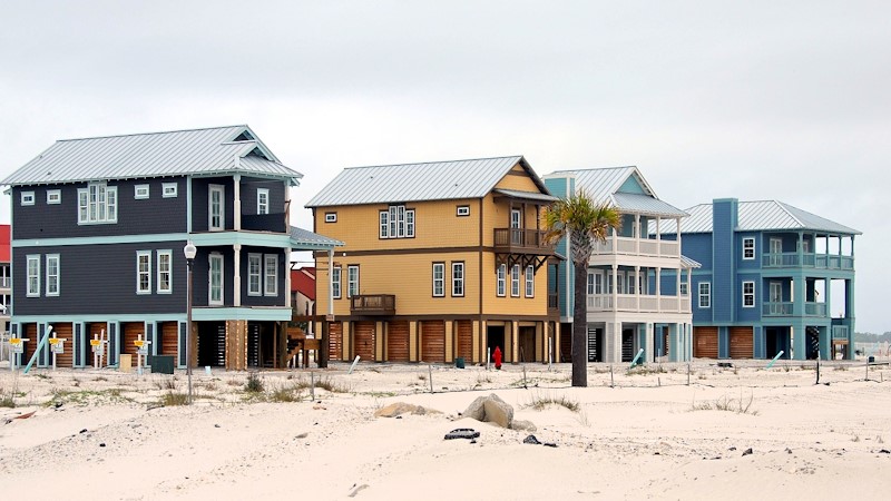 Beach houses directly on the beach in various colors, it is a cloudy day.