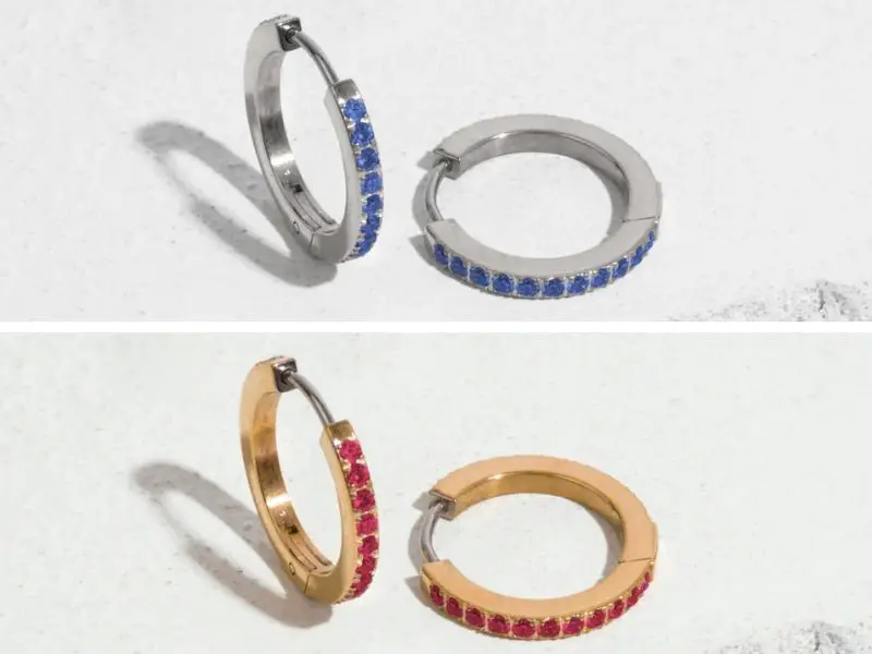 Two pair of Tini Lux brand birthstone hoop earrings. The top image has a pair of titanium hoop earrings with blue gems inlaid. The bottom photo has gold earrings with red stones.