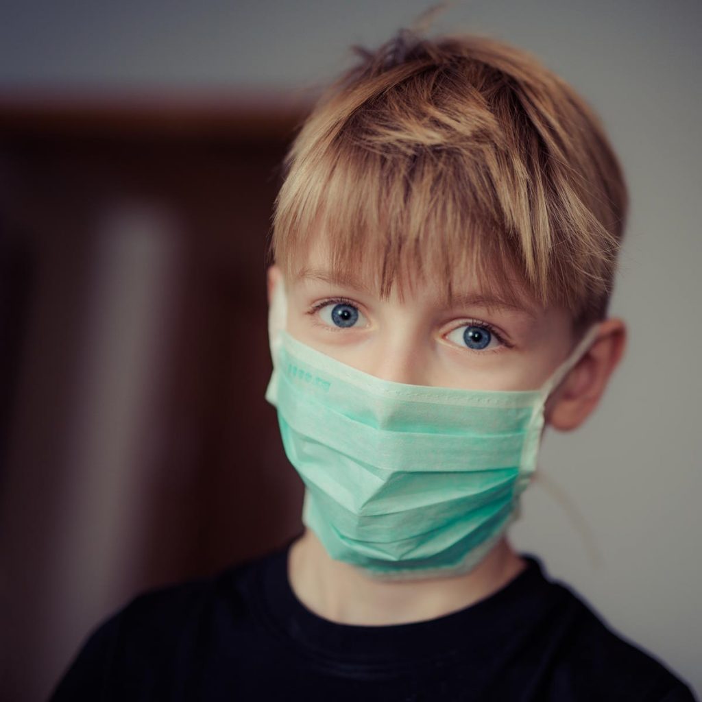 boy wearing a disposable mask over his mouth and nose.