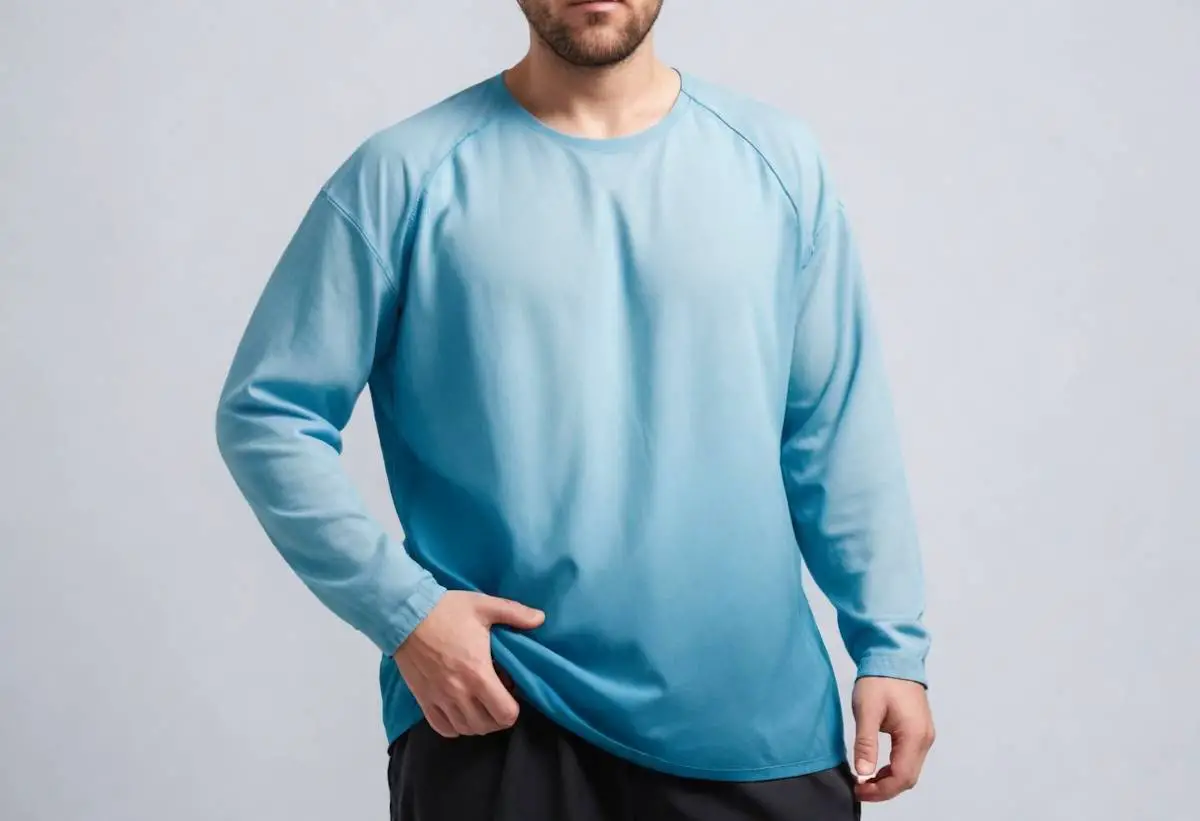 A man slightly lifting up his baggy, loose fitting blue shirt.