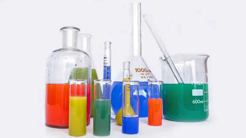 Scientific instruments and containers holding various colored chemicals and solvents.