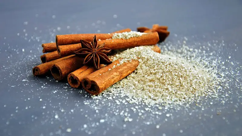 Many cinnamon sticks laying in cinnamon sugar.
