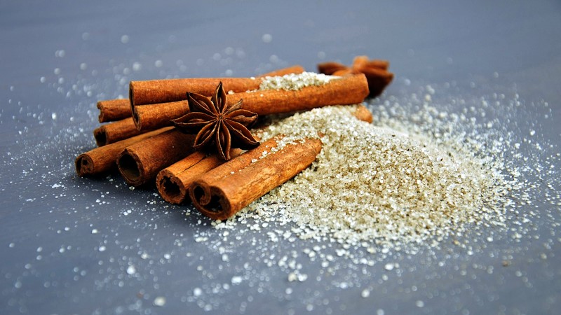 Many cinnamon sticks laying in cinnamon sugar.