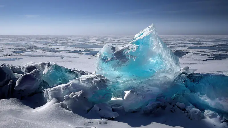 A light blue frozen ice chunk in the ocean.