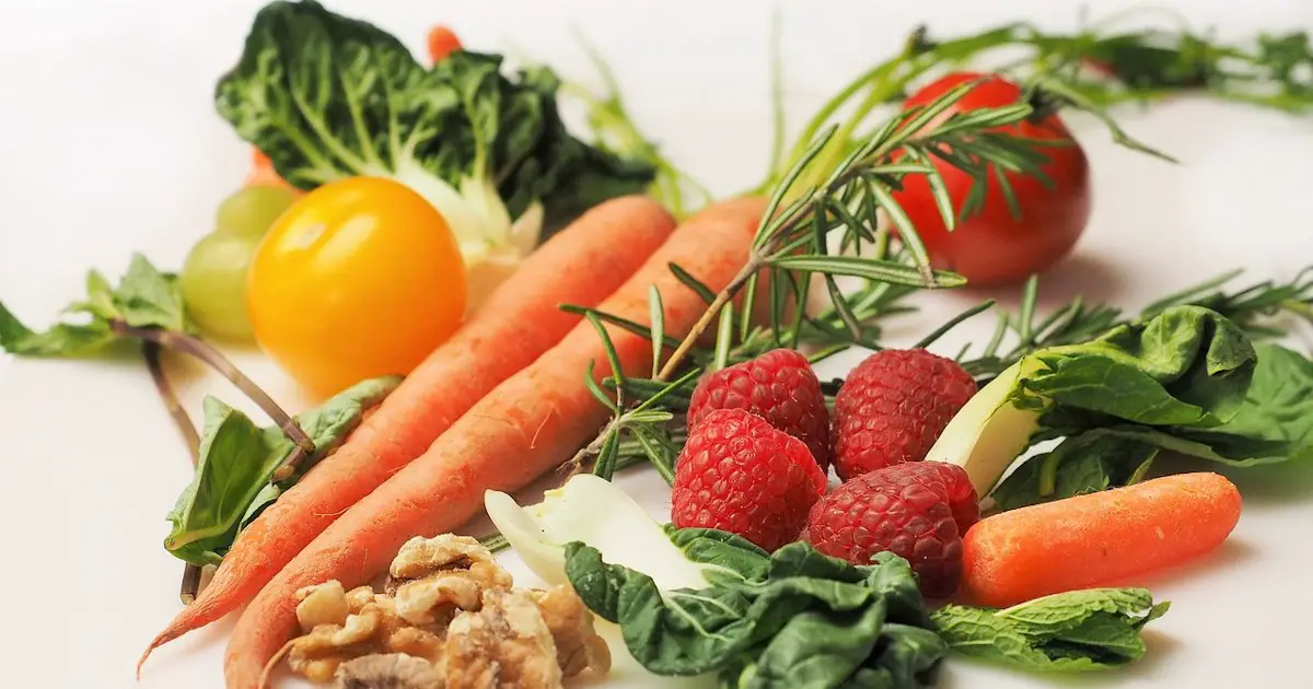An array of fresh fruits and vegetables to include carrots, raspberries, spinach, and nuts.