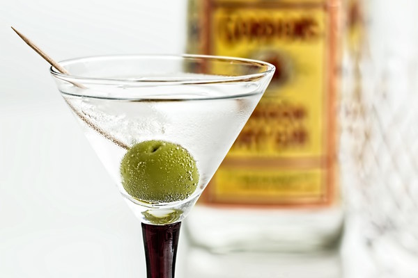 a gin martini with a green olive in the drink