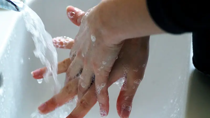 close up of someone washing their hands with soap and water.