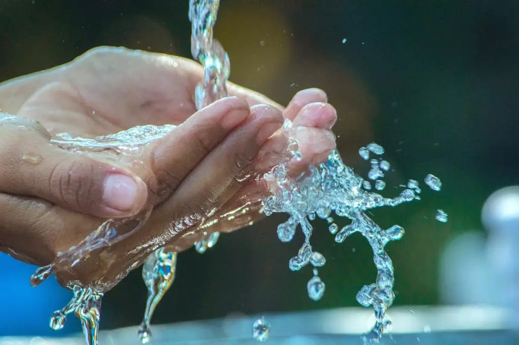 person rinsing hands under running water