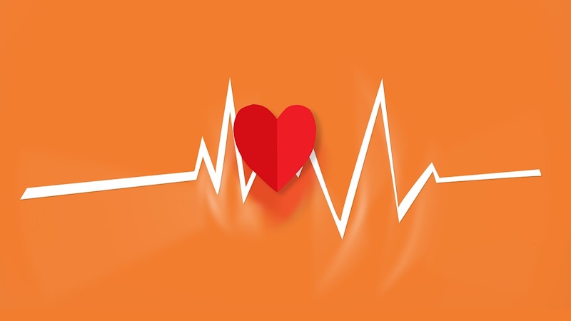 A paper heart over an EKG heartbeat, with an orange background.