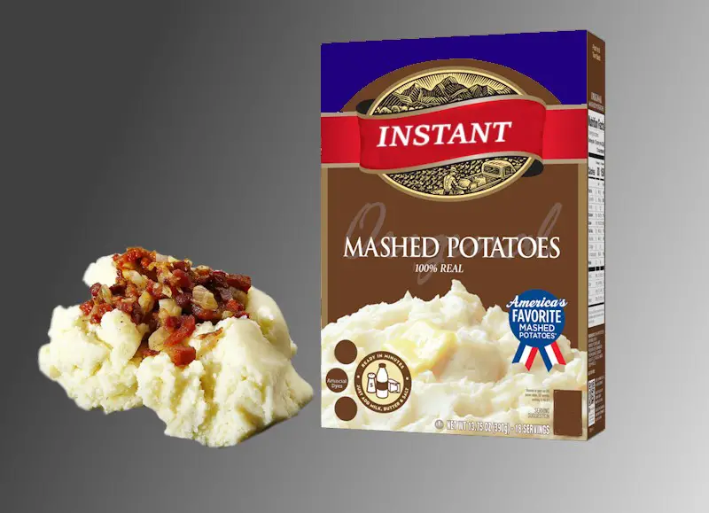 A box of instant mashed potatoes, with some cooked potato flakes next to the box.