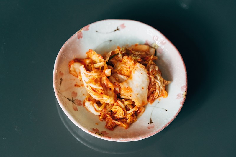 A decorative plate that has a serving of fermented kimchi.