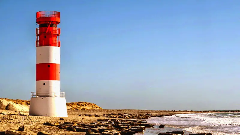 A lighthouse on the shore of a beach.