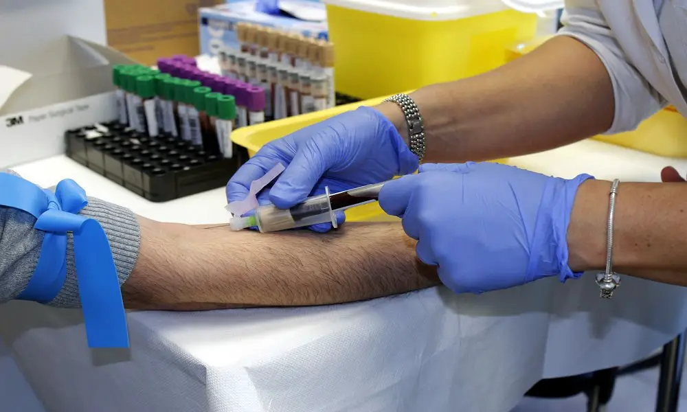 a Lab Technician is drawing the blood from a patient for testing.