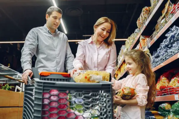A family shopping at the grocery store and placing food into the cart.
