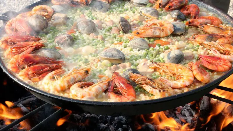 A large pot full of seafood and shellfish being cooked over an open fire.