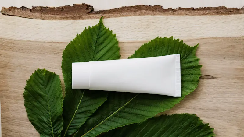 a white squeeze tube of cream, resting on a leaf.