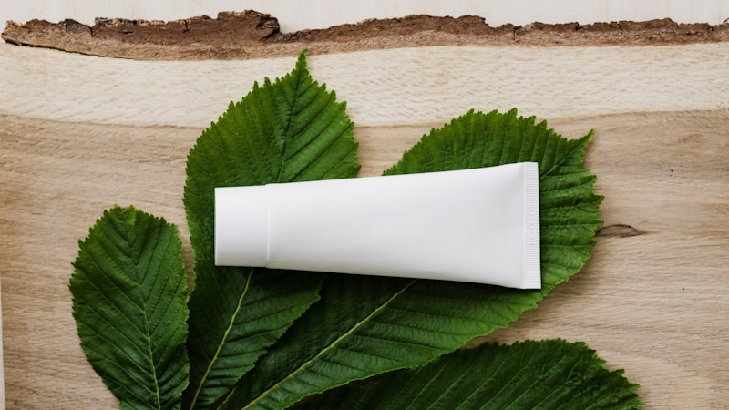 a white squeeze tube of cream, resting on a leaf.