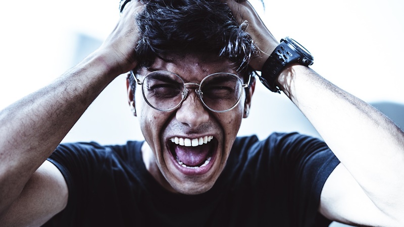 Stressed man who is screaming and pulling out his hair.