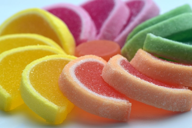 many sugary fruit slices in all colors presented on a white background.