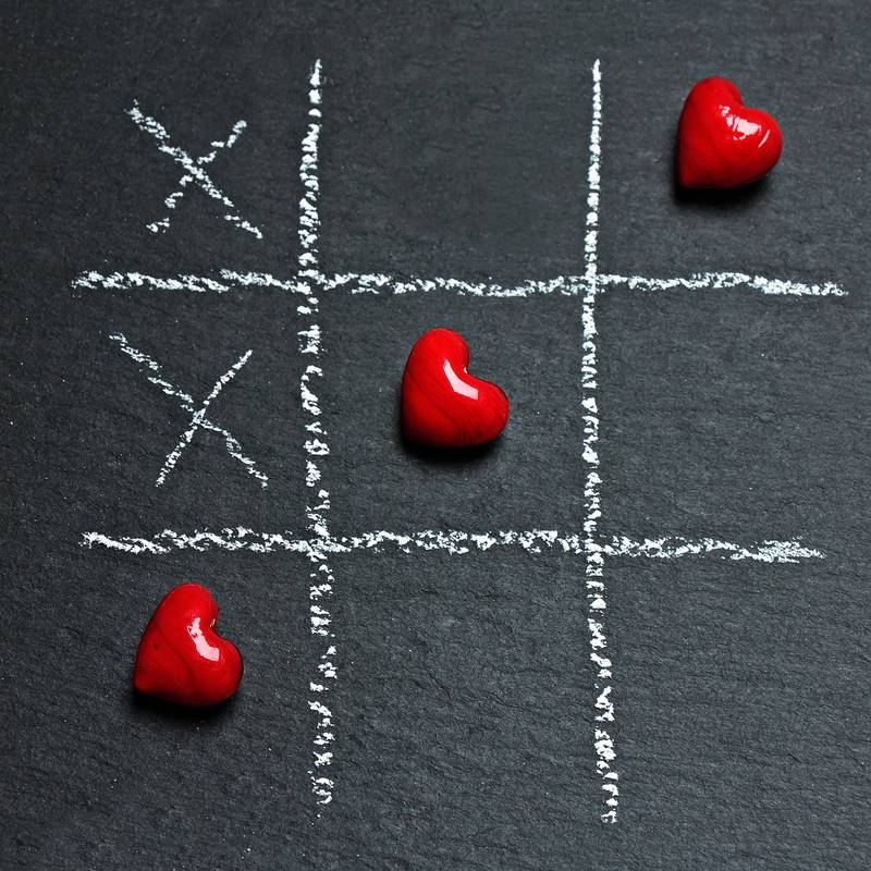 A chalk tic-tac-toe board with candy hearts as the "o's"