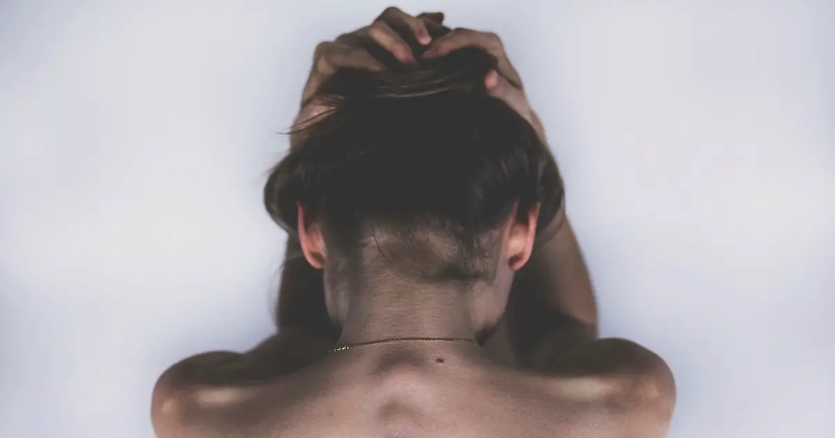 woman holding her hair up with her shirt off, showing her back.