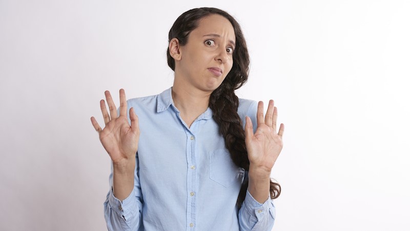 Woman with her hands up, making a face like she is scared.