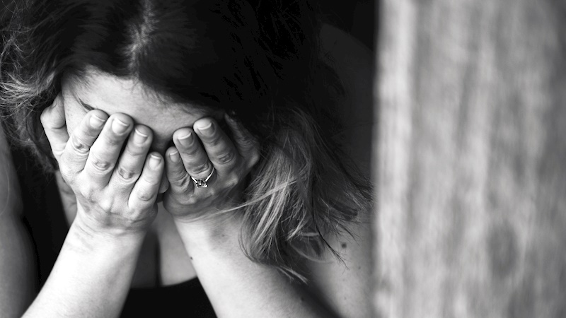 woman with her face in her hands because of stress and anxiety. She is upset.