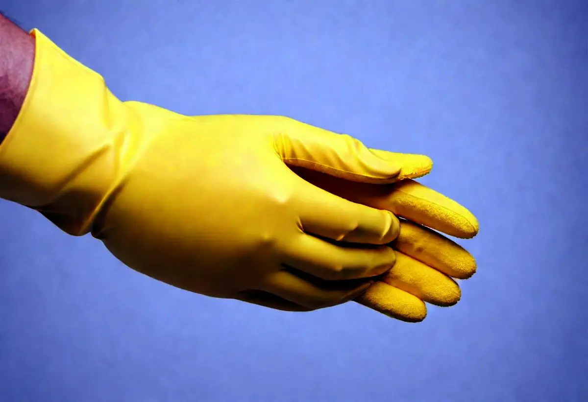 Hands that are wearing yellow cleaning gloves to keep his skin protected.