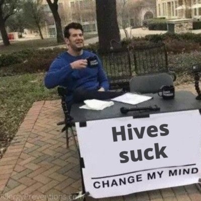 change my mind meme of a man sitting at a table drinking coffee with a sign that states “Hives suck, change my mind” 