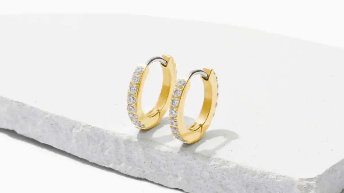 Pair of titanium earrings that are gold hoops with crystals around the hoops.