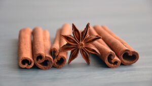 Rolls of cinnamon bark, dried on a table, with a star seed pod in the middle of the cinnamon sticks.
