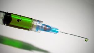 allergy immunization needle and syringe with green liquid inside.