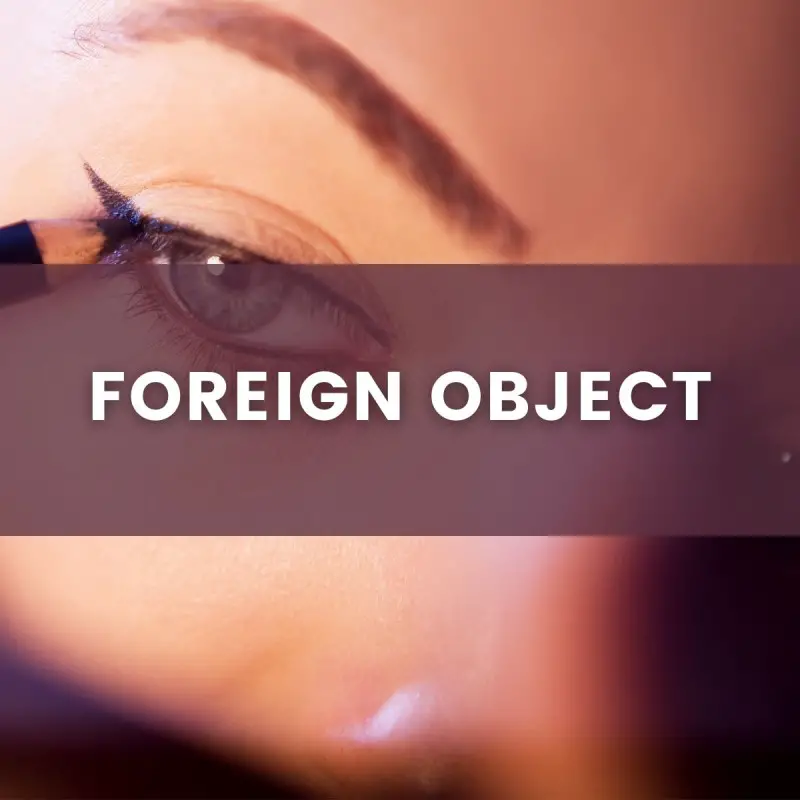 close up of a woman putting on eye liner with a pencil, text inlay says "foreign object"