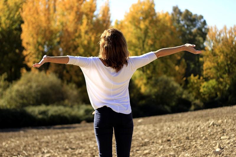 Woman standing outdoors with her arms held open signifying freedom.